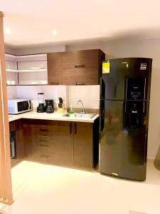 La cuisine est équipée d'un réfrigérateur noir et d'un évier. dans l'établissement Hermoso Apartaestudio Norte de Barranquilla, à Barranquilla