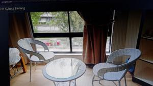 3 Stühle und ein Tisch vor einem Fenster in der Unterkunft Homestay KNK in Tawau