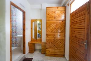 a bathroom with a wooden door and a mirror at Luvya Retreats Hotel in Manāli