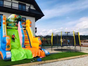 un parque infantil con una casa hinchable y un rebote inflable en Aparthotel Rabiań-SKI zewnętrzny basen oraz jacuzzi z podgrzewana wodą dmuchaniec i 2 place zabaw w cenie en Białka Tatrzanska