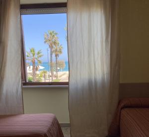 een slaapkamer met een raam met uitzicht op de oceaan bij Hotel Promenade in Porto SantʼElpidio