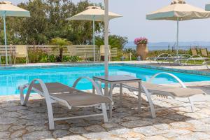 ein Tisch und zwei Stühle und Sonnenschirme neben einem Pool in der Unterkunft Castello Antico Hotel in Gythio