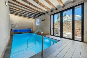 a swimming pool in a house with windows at Arassa casa rural in Rocafort de Queralt