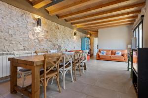 a dining room with a stone wall and a table and chairs at Arassa casa rural in Rocafort de Queralt