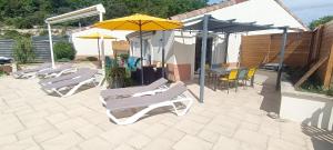 a group of chairs and umbrellas on a patio at Gîte myosotis Piscine Privée 4 Chambres in Lagorce