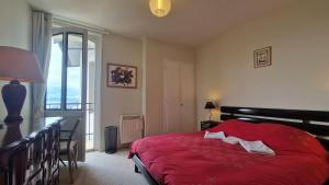 a bedroom with a red bed with a red blanket at Grand Appartement La Source d'Evian in Évian-les-Bains