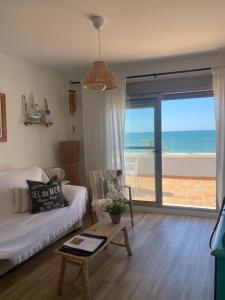 a living room with a couch and a view of the ocean at Ático Al Sol en primera línea de playa in Rota