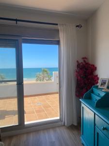 a room with a sliding glass door with a view of the ocean at Ático Al Sol en primera línea de playa in Rota