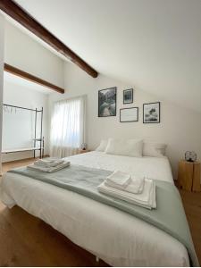 Design Apartment in the heart of Bolzano في بولسانو: غرفة نوم بسرير ابيض كبير عليها مناشف
