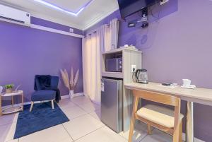 uma cozinha com paredes roxas e uma mesa e cadeiras em Botle Ba Afrika Lodge em Vereeniging