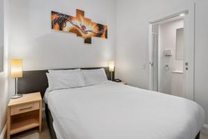 a bedroom with a large white bed and two lamps at Studio Gem in the Heart of Melbourne in Melbourne