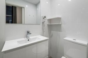 a white bathroom with a sink and a mirror at Studio Gem in the Heart of Melbourne in Melbourne