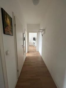 um corredor com paredes brancas e piso de madeira em Wohnung in Köln em Colónia