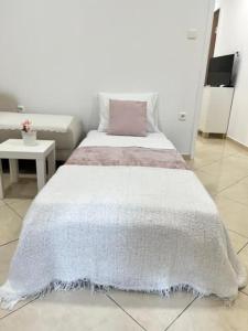 a bedroom with a white bed with a pink pillow at Cozy apartment near Airport in Koropi