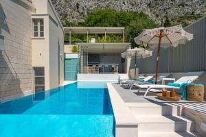 a pool with chairs and umbrellas next to a building at Casa GENI-heated pool, 3 bedrooms, sea views in Omiš