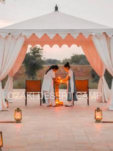 una sposa e uno sposo che accendono una candela sotto una tenda di Ozaki Desert Camp a Jaisalmer