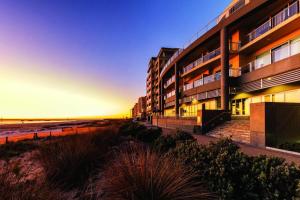 ein Gebäude am Strand neben dem Meer in der Unterkunft Pier Apartment - Glenelg Views - No 506 in Adelaide