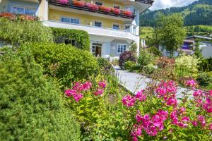 ogród z różowymi kwiatami przed budynkiem w obiekcie Hotel Garni Mühlbacher - inklusive kostenfreiem Eintritt in die Alpentherme w mieście Bad Hofgastein
