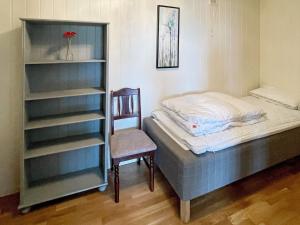 1 dormitorio con 1 cama y 1 silla junto a un estante de libros en Two-Bedroom Holiday home in Farstad 1, en Farstad