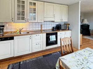 cocina con armarios blancos, fregadero y mesa en Two-Bedroom Holiday home in Farstad 1, en Farstad