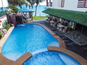 a swimming pool in front of a resort with the ocean at Badladz Staycation Condos in Puerto Galera