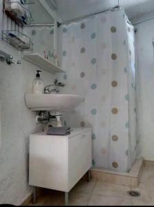 uma casa de banho com um lavatório e uma cortina de chuveiro com bolinhas em Traditional House in Elounda em Elounda