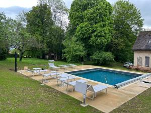 einen Pool mit Liegestühlen und einem Tisch in der Unterkunft LE PARC in Coulanges-sur-Yonne