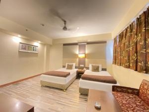 a hotel room with two beds and a couch at Astoria Hotel in Kolkata