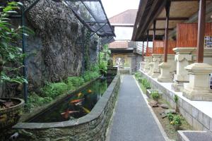 a koi pond in a building with a stone wall at Belvilla 93916 Budi House Near Ubud Palace in Ubud