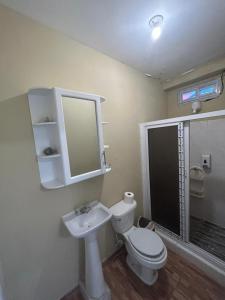 uma casa de banho com um WC, um lavatório e um espelho. em Villas La Romana #2 em La Ceiba