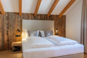 1 dormitorio con cama blanca y pared de madera en Moarhof Ums, en Umes