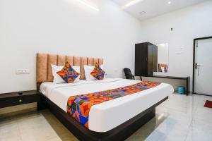 a bedroom with a large bed with colorful sheets at FabHotel Saroj Inn in Nashik