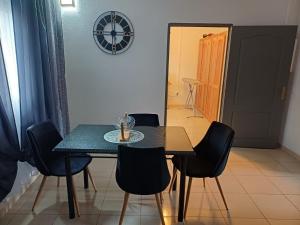 a dining room table with chairs and a clock on the wall at Appartement T3 Passamainty in Mamoudzou