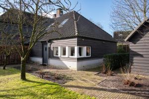 a black and white house with a tree in the yard at B&B aan het Dijksteegje in Sint-Oedenrode