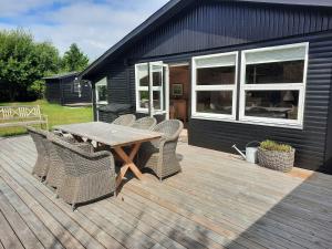 een houten terras met een houten tafel en stoelen bij Cozy Summer House In Lnstrup For 5 People, in Lønstrup