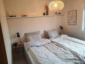 Cozy Summer House In Lnstrup For 5 People, في لونستروب: غرفة نوم بسرير ذو شراشف ووسائد بيضاء