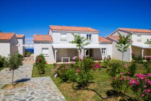 ein großes weißes Haus mit rosa Blumen im Hof in der Unterkunft Villa climatisée T3 piscine chauffée accès direct à la plage de Prunete in Cervione