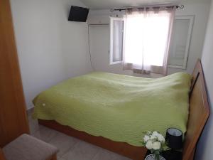 ein Schlafzimmer mit einem grünen Bett und einem Fenster in der Unterkunft Villa climatisée T3 piscine chauffée accès direct à la plage de Prunete in Cervione