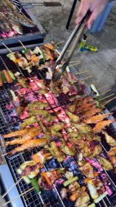 una persona cocinando comida en una parrilla con pinzas en Kawaland glamping resort, en Telukbakau