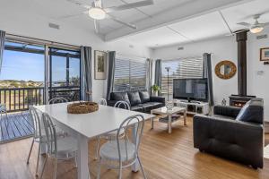 Una sala de estar con una mesa y sillas blancas. en Carrickalinga SeaHaven, en Normanville