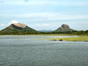 a river with two mountains in the background at Sigiriya Village in Sigiriya