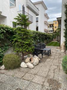 un jardín con un banco y un árbol y rocas en Villa Nancy Affittacamere, en Cimitile