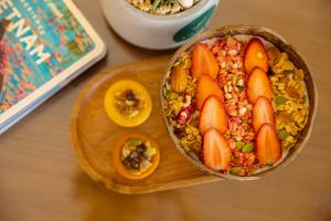 a bowl of food on a wooden cutting board with fruit at SOLÉA Hotel GrandWorld Phu Quoc in Phú Quốc
