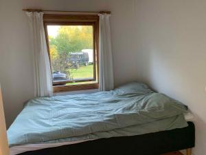 uma cama num quarto com uma janela em Cozy Summer House Close To The Beach, em Gilleleje