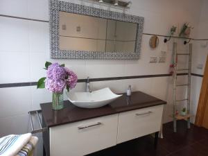 ein Badezimmer mit einem Waschbecken und einer Vase aus lila Blumen in der Unterkunft Casa moderna con jardín, 2 habitaciones in Santa Cruz de Bezana