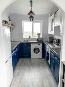 a kitchen with blue cabinets and a washing machine at Beachfront Artsy Apartment in Clacton-on-Sea