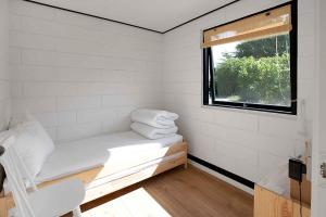 um pequeno quarto branco com uma janela e um banco em Summer House In An Idyllic Coastal Area, em Højby
