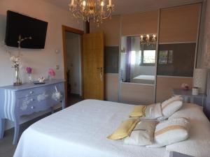 ein Schlafzimmer mit einem großen weißen Bett und einem Kronleuchter in der Unterkunft Casa moderna con jardín, 2 habitaciones in Santa Cruz de Bezana