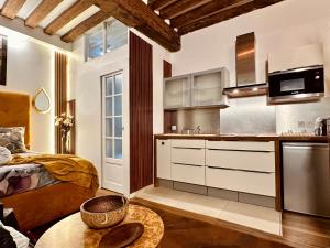 パリにあるLuxury Studio design by KENZO renovate in May 2024の白いキャビネットとテーブル付きのキッチンが備わります。