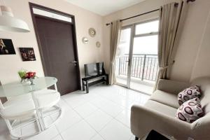 een woonkamer met een glazen tafel en een balkon bij OYO 93940 Apartemen Mekarwangi Square By Lina in Bandung